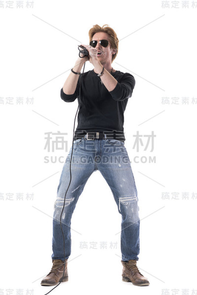 激情四射的年轻摇滚歌手戴着太阳镜在麦克风上唱歌。