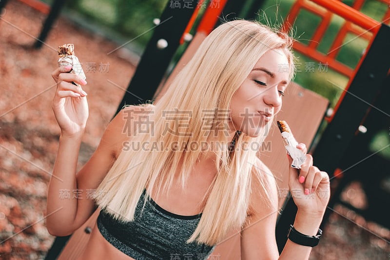 美丽饥饿的健身女孩享受蛋白质棒