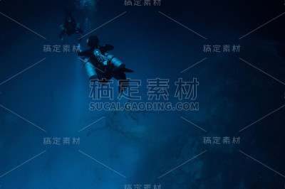 图为两名潜水员在坑底用手电筒和气泡拍照