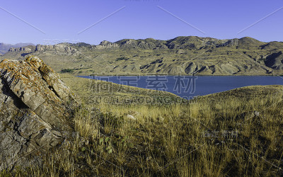 崎岖的草原与巨石和河流与山脉的背景。