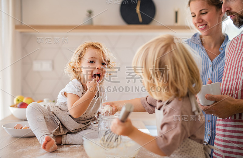 年轻的家庭和两个小孩在厨房里做饭。