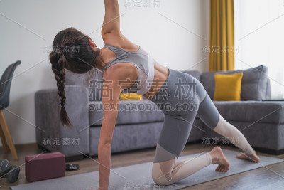 在家里练习现代瑜伽的女性。延伸侧角姿态