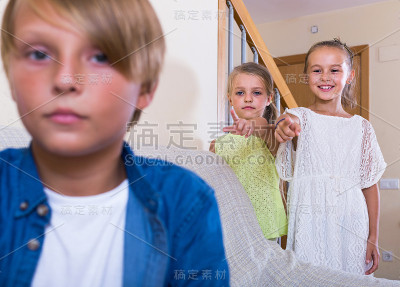 两个女孩在聊天，一个愠怒的男孩分别坐在家里