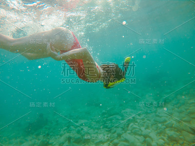 在水下穿着红色泳衣的女人戴着潜水面罩和脚蹼