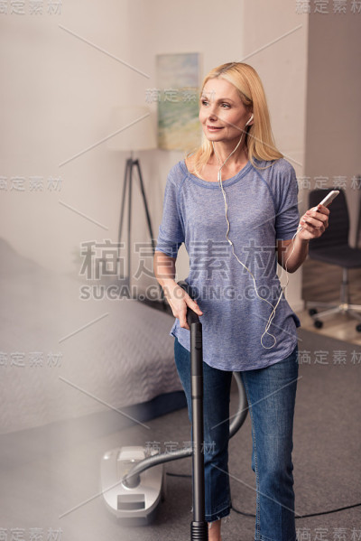 用智能手机和吸尘器的女人