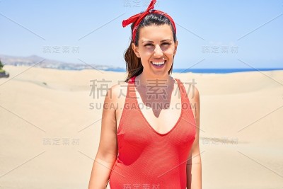 年轻美丽的女人日光浴穿着夏季swinsuit在马斯帕洛马斯沙丘bech