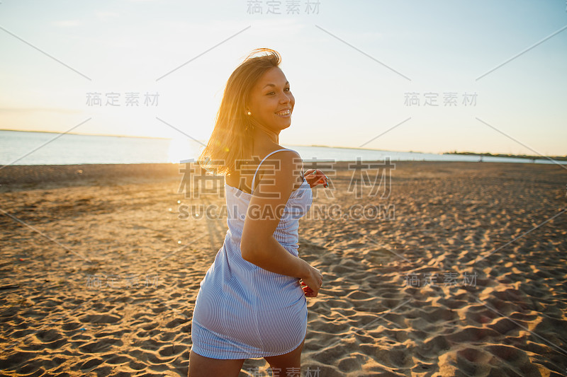 俏皮性感的女人有乐趣在海滩上的日落。快乐的年轻女人完美的身材穿着性感的衣服