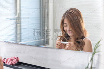近距离的微笑女人化妆刷近脸和看镜子。亚洲美女