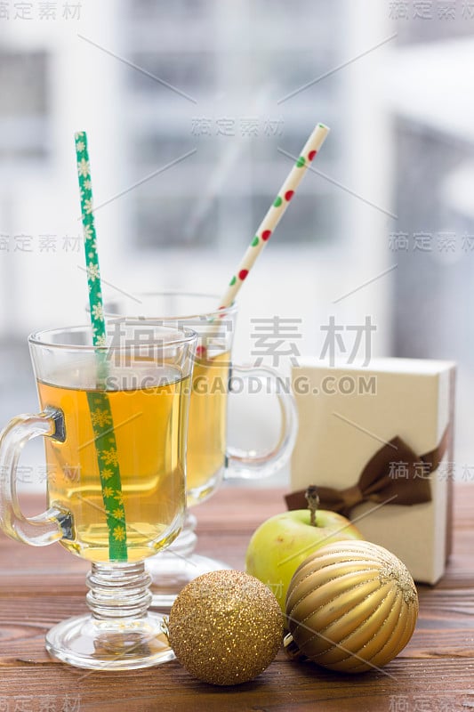 两个带吸管的茶杯，一个礼品盒，一个苹果和一个圣诞树球