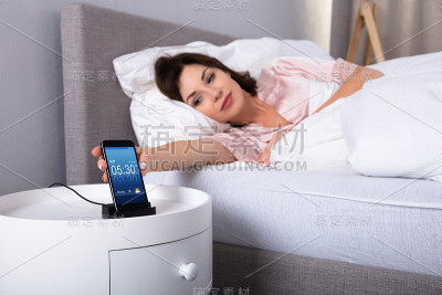手机上的女性打盹闹钟