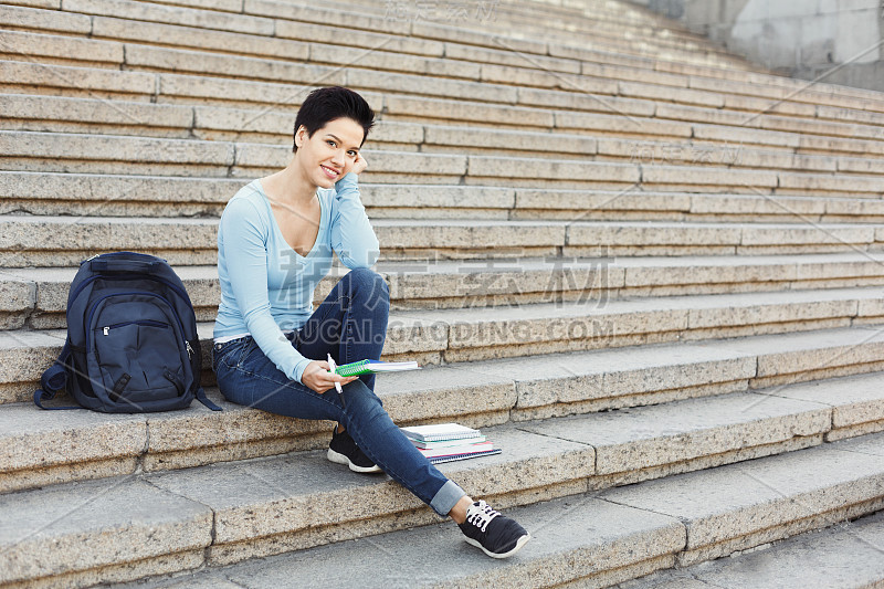 年轻微笑的女学生在笔记本上做笔记