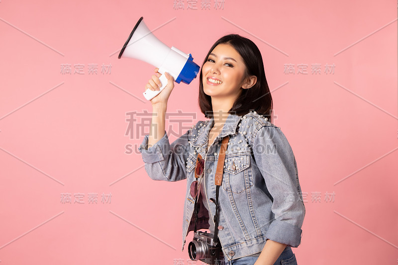 夏日休闲装的女游客。亚洲微笑的女子。以粉红色为背景出国旅行的乘客。她要去度暑假了。假日信用卡。