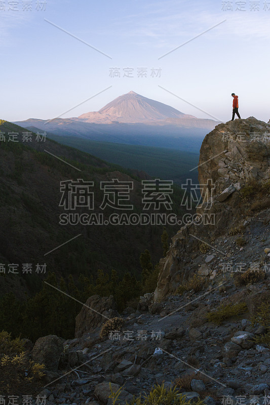 一个女人站在悬崖上，背景是火山