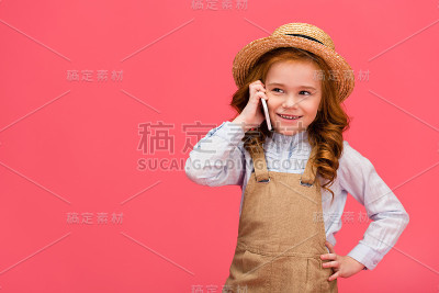 一个微笑的孩子在用智能手机聊天的照片被隔离在粉红色上
