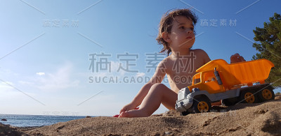 一个小男孩在海滩上玩玩具卡车