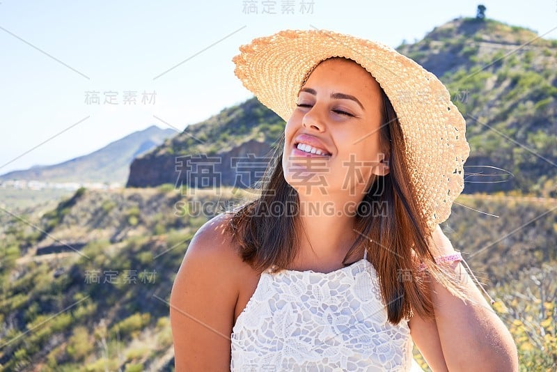 年轻美丽的女子在山上享受着暑假的风景，旅行者女孩笑得很开心