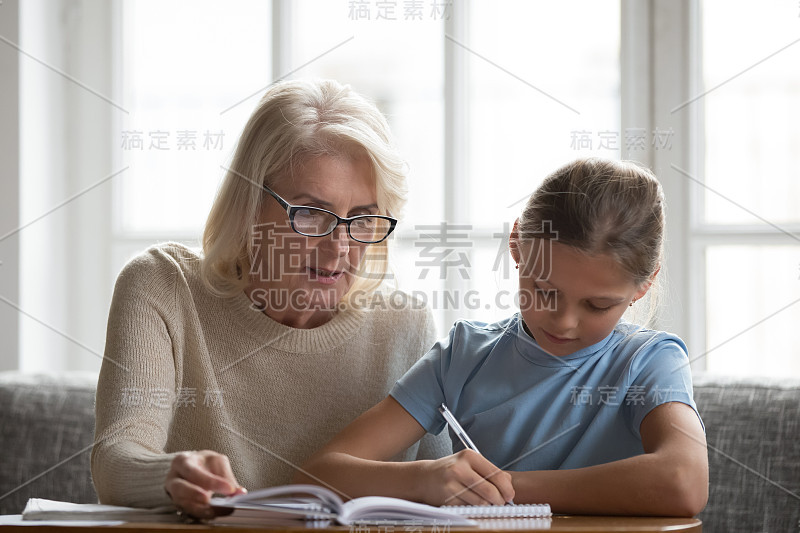 年长的家庭教师帮助女学生做家庭作业