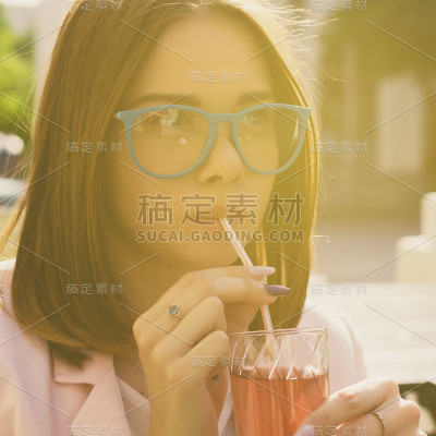 年轻漂亮的女孩喝着冷饮，在户外