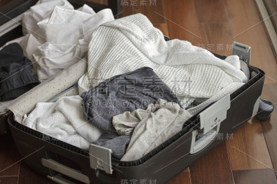 度假旅行回家前装满旧衣服和脏衣服的手提箱。
