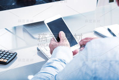 在办公桌上用移动设备打字的匿名商人
