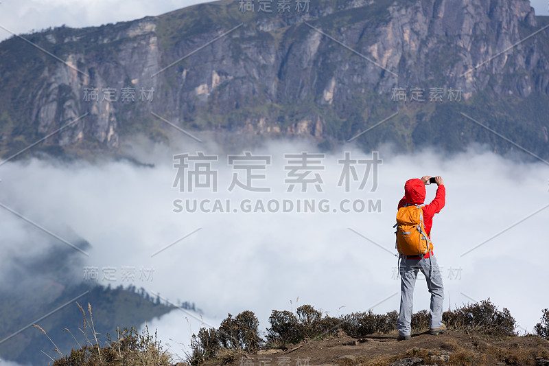 成功女背包客在山顶悬崖边自拍