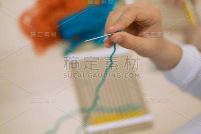 在学校艺术治疗课上，孩子们用手织布机