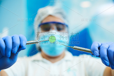 牙科仪器在一个模糊的牙医手中做牙科检查在一个模糊的蓝色背景