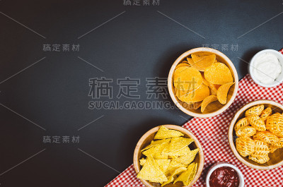 薯片和零食放在黑色的石板桌上，俯视图