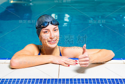 年轻快乐的女人在游泳池里竖起大拇指