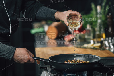 厨师将白葡萄酒与香菇片倒入平底锅中