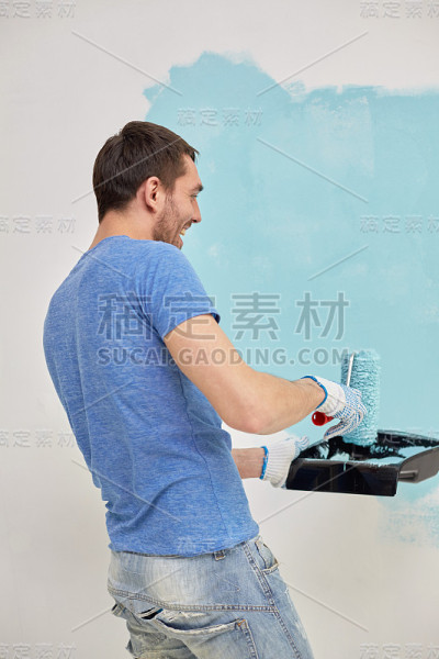 微笑的男人画着家里的墙