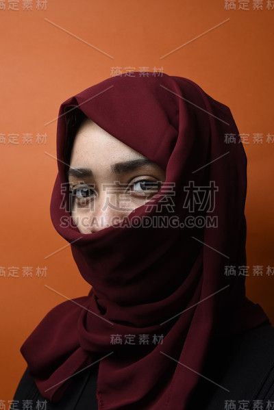 美丽的女人用头巾遮住她的脸。时尚的穆斯林风格的女孩包裹在围巾