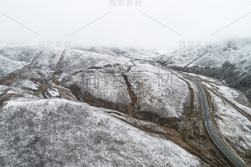 蜿蜒穿过被雪山环绕的山谷的乡村道路