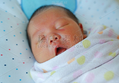 在毯子里微笑的亚洲婴儿的特写脸。
