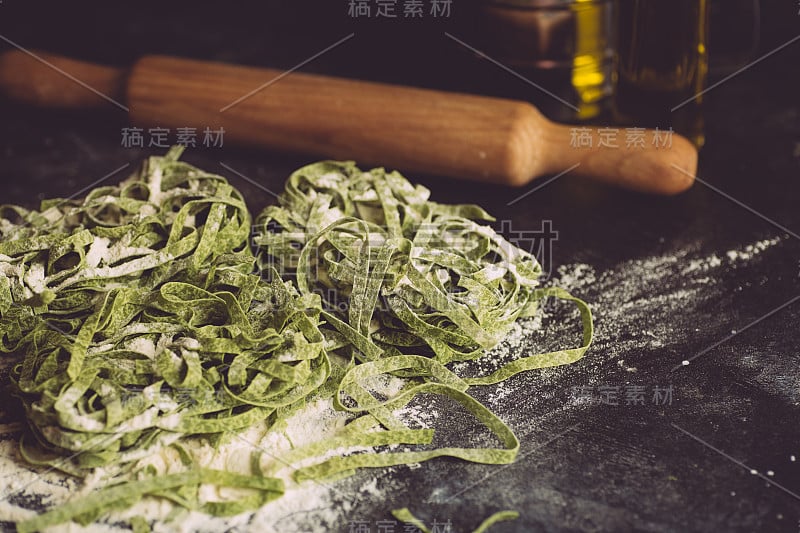 意大利面食的背景。纯素食意大利面食与新鲜的菠菜(菠菜宽面条阿尔弗雷多面食)在一个黑暗的背景。旧厨房背