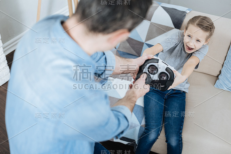 恼怒的小女孩拿着她的虚拟现实头盔大喊大叫