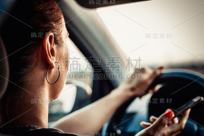 一个女人用手机开车的特写。