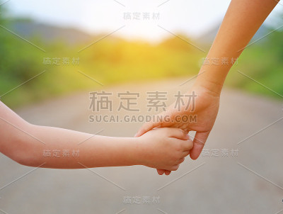 靠近姐姐的手与孩子走在路上的射线阳光。