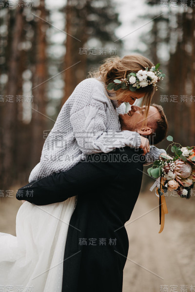 新婚夫妇在松树林中的小路拥抱。