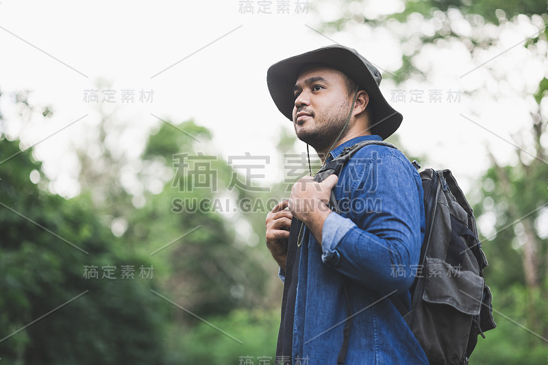 年轻帅气的男人背着背包正在独自走在路上。人们期待一次有趣的旅行。