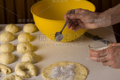 女性用手在生百吉饼上撒糖粉