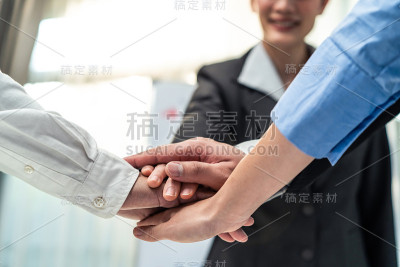 在会议室里，一群商人和妇女双手合十，为企业的成功而欢呼。同事员工团队头脑风暴，工作团队团结一致。