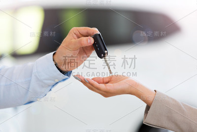 汽车销售员在陈列室向女士递车钥匙