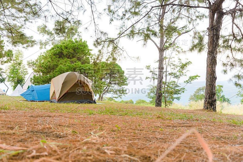 游客帐篷在日落的草地上俯瞰群山。在户外野营