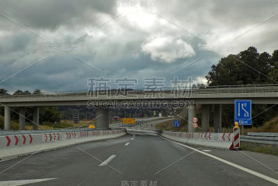 高速公路出口有立交桥和多种道路标志:禁止超车和限速