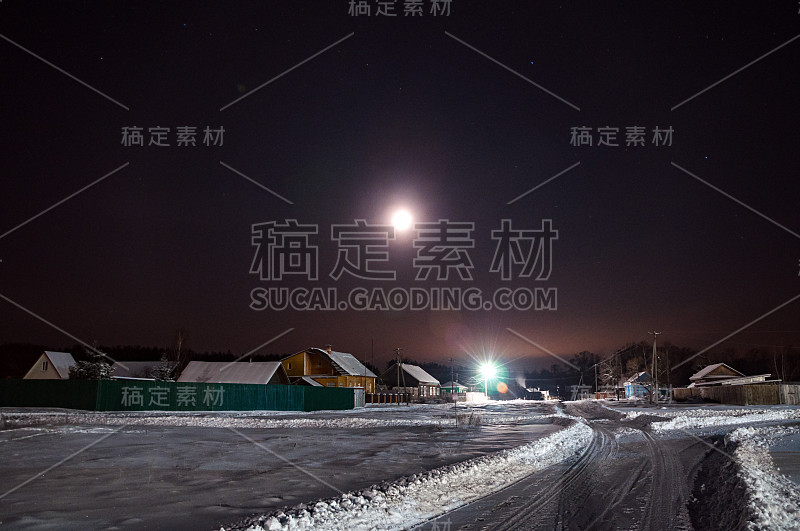 冬夜白雪覆盖的道路。围绕着寂静的星空和月亮的光环。