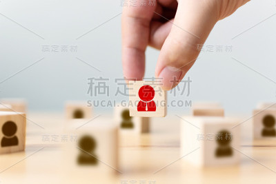 一个商人的手选择一个木方块与图标人物从人群中脱颖而出。成功的商业团队领导理念