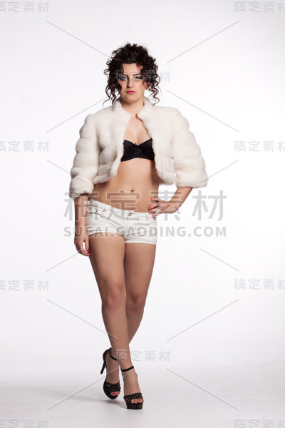 穿着白色裘皮大衣和短裤的年轻卷毛女人
