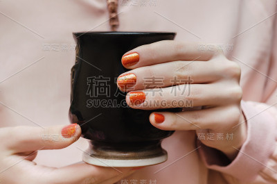 女性的手与橙色指甲设计。