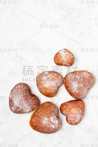 白色背景上撒着糖粉的自制心形甜甜圈。美味的甜甜圈，拷贝空间